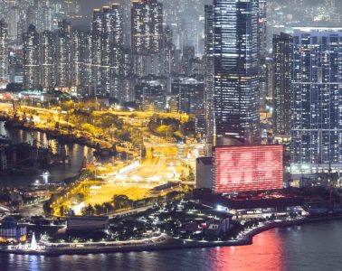 At night, Hong Kong’s dense skyline rises above the harbour, with illuminated high-rises and bright waterfront roads.