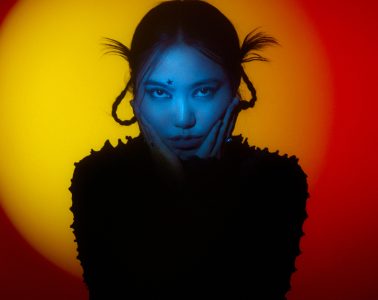 A blue-lit portrait of Miu Zyu shows a woman with braided hair and a black textured garment against a red and yellow glow.